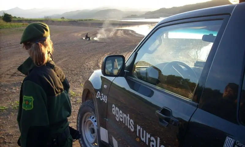 Agente rural avistando una hoguera ilegal en la orilla de un rio